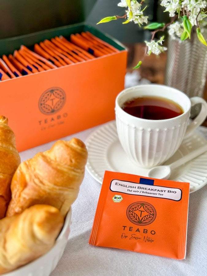 Un sachet English Breakfast Teabo, une tasse et des viennoiseries